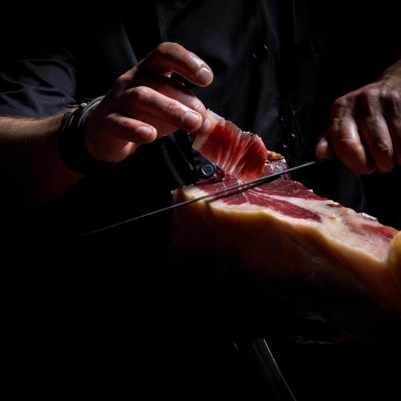 hombre cortando jamon iberico